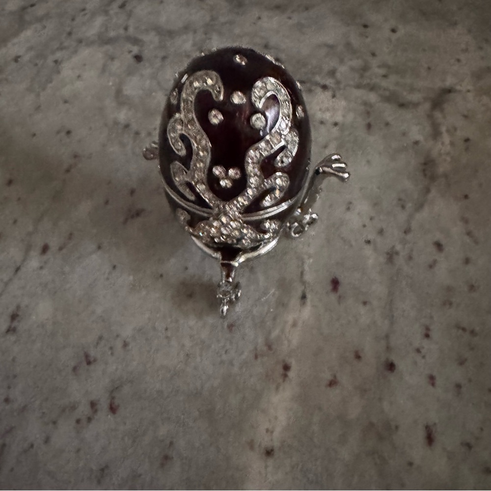 black and silver egg surrounded by clear gems that opens to hold small trinkets